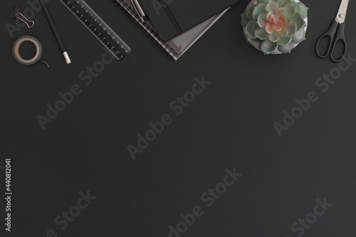 Black leather office table with notebook, stationery and green plant. Top view with copy space. Flat lay composition.