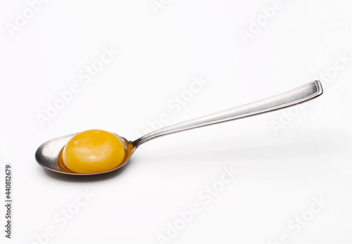 Fresh egg yolk on spoon on white background.