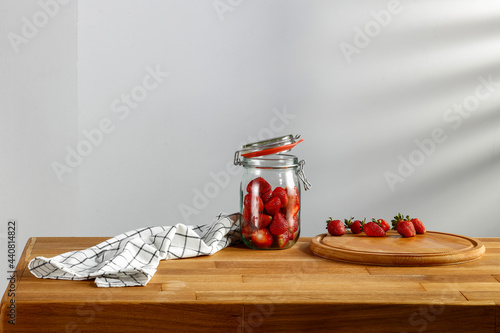 Fresh strawberries on a wooden kitchen table and shadow on the wall 