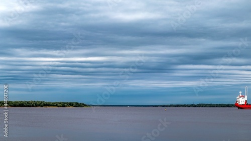 Cloudy sky above the water surface of a large river. Marine vessel in the roads. Northern Dvina  Arkhangelsk  Russia