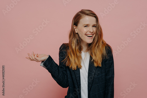 Laughing young woman with tipping hand shrugging shoulders photo