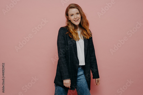 Stylish fashionable young woman wearing plaid blazer and jeans posing in studio