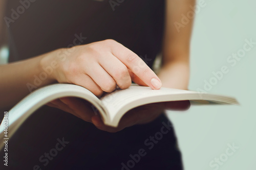 Girl holding an open book in her hands, close-up. photo