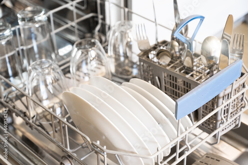 Dishwasher with clean white plates and steel cutlery