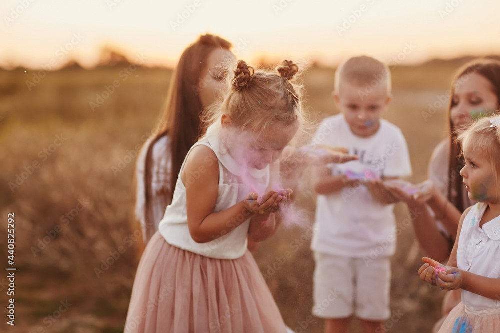 Fototapeta premium happy young moms playing with their kids outdoors in summer. Happy family time together concept. selective focus. Holi color festival.