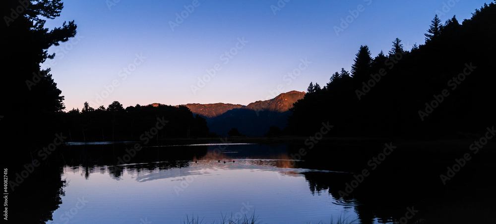 Obraz premium Panoramic landscape of beautiful sunrise or sunset on an alpine lake in the Pyrenees, Catalonia, Spain. Concept of vacations, summer, relaxation and disconnection in nature. Wilderness.