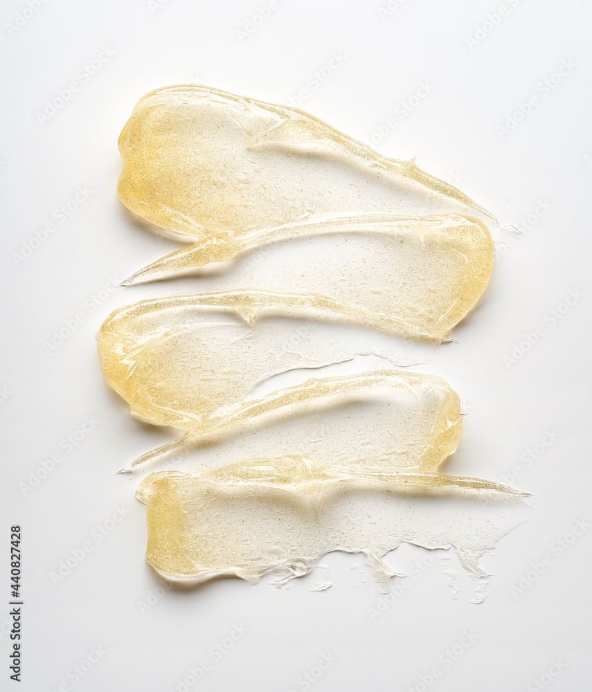 Transparent smear and texture of golden cosmetic gel on a white background. Transparent smear and texture of golden cosmetic gel on a white background.