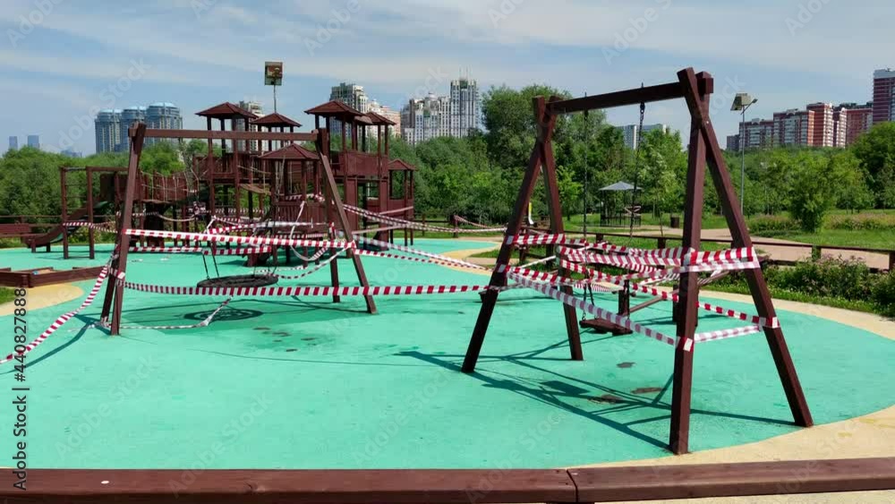 Closed outdoor child playground in sunny day in city park in Moscow, Russia. No children. Barricade tapes swings on the wind. Illness prevention theme. Closed outdoor child playground in sunny day in city park in Moscow, Russia. No children. Barricade tapes swings on the wind. Illness prevention theme.