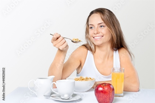 Portrait of a happy pretty young woman eating porridge from a bowl.