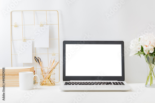Home office workspace with laptop mockup and mood board, books, office supplies on a light background