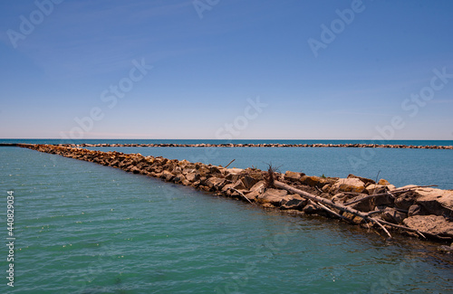 Fototapeta Naklejka Na Ścianę i Meble -  Jetty of Rocks in Lake Bay Under Blue Sky