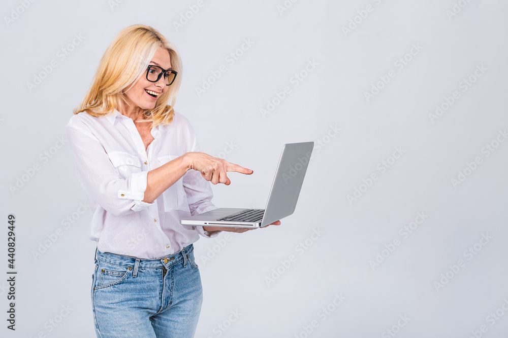 Photo of amazed shocked surprised senior mature old woman holding laptop computer isolated on white grey background. Photo of amazed shocked surprised senior mature old woman holding laptop computer isolated on white grey background.
