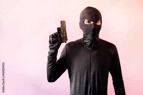 Fototapeta Naklejka Na Ścianę i Meble -  Robber man dressed in black with gun