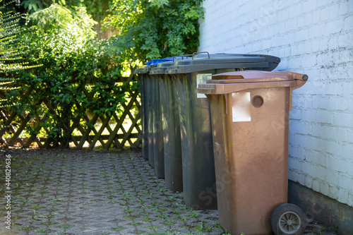 different rubbish bins placed in a row on a house wall