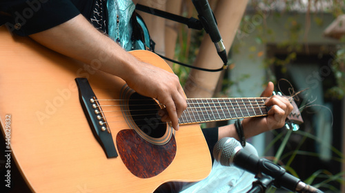 The young man plays hands and on a classic acoustic wooden guitar on the street