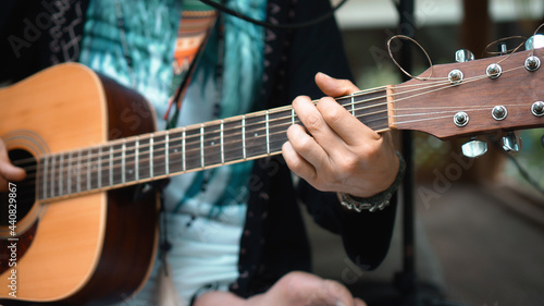 The young man plays hands and on a classic acoustic wooden guitar on the street