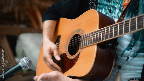 The young man plays hands and on a classic acoustic wooden guitar on the street