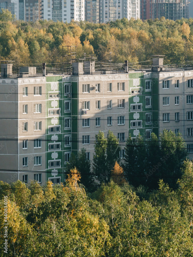 Soviet architecture panel multi-storey residential building fasad at summer days among the trees