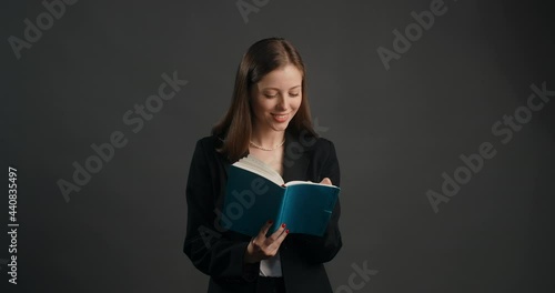 Young woman in black suit listens to the collocutor with smile and makes notes to the paper notepad, taking survey, making interview, 4k Prores HQ photo