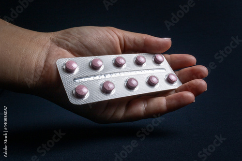 A pink medicine pack used for seasickness when you are sick or in discomfort. Held by the hand of a white woman. They have a black background and must be used with a prescription.
