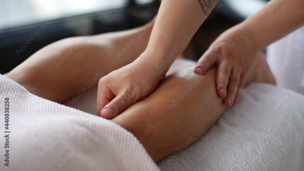 Close-up hands of unrecognizable male masseur doing sports massage of lower leg to athlete in massage spa salon. Professional physiotherapist with strong hands performing foot and lower leg massage. Close-up hands of unrecognizable male masseur doing sports massage of lower leg to athlete in massage spa salon. Professional physiotherapist with strong hands performing foot and lower leg massage.