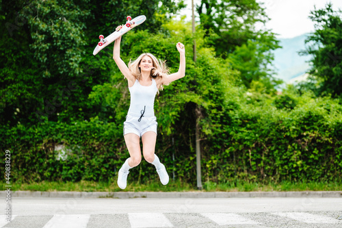 The girl jumps with the skateborad in her hand.