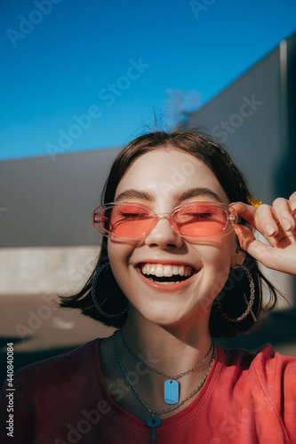 Teenager wearing sunglasses smiling widely with closed eyes while spending summer