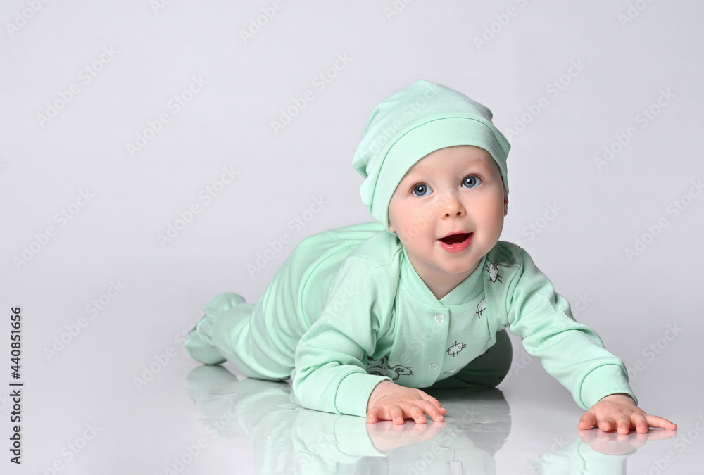 joyful baby infant A toddler in a cotton jumpsuit and a matching cap learns to crawl. joyful baby infant A toddler in a cotton jumpsuit and a matching cap learns to crawl.