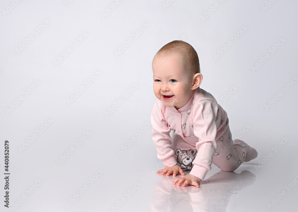 Cute infant baby in pink bodysuit Suit with socks learning crawling and walking on bright studio background Cute infant baby in pink bodysuit Suit with socks learning crawling and walking on bright studio background