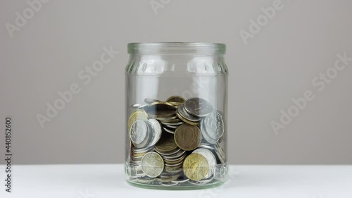Decrease of coins in the glass jar - stop motion footage. Saving money concept.