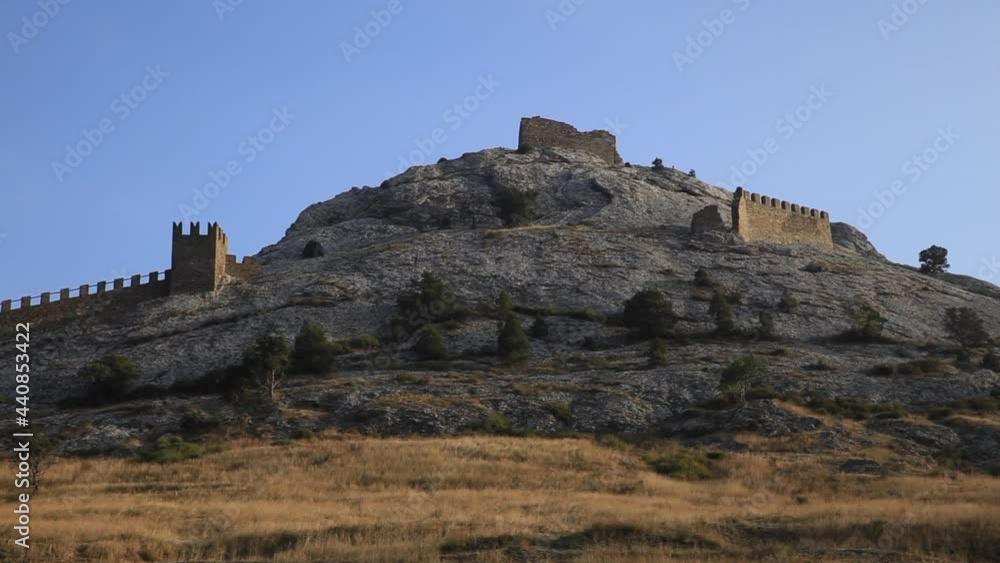 Bottom view of ancient Genoese fortress in Sudak town. Historic architectural landmark at sunset. Crimea. Bottom view of ancient Genoese fortress in Sudak town. Historic architectural landmark at sunset. Crimea.