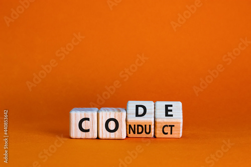Code of conduct symbol. Turned the wooden cube and changed the word code to conduct. Beautiful orange background. Business and code of conduct concept. Copy space.