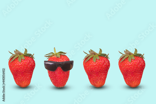 Creative idea with outstanding red strawberry with goggles and fresh ripe strawberries on pastel blue background.