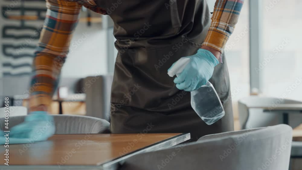 Close up of man in protective gloves cleaning table for clients Close up of man in protective gloves cleaning table for clients