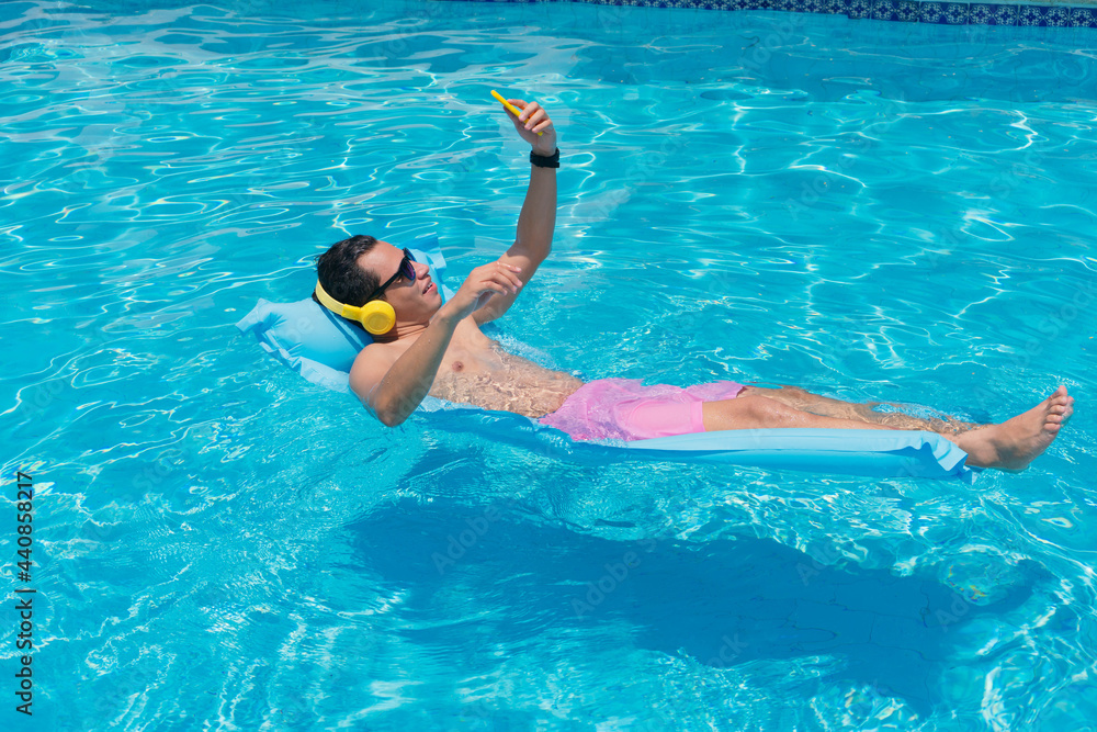 Young Latino man at the pool using his cell phone.