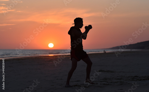 a fighter training on the beach at sunset