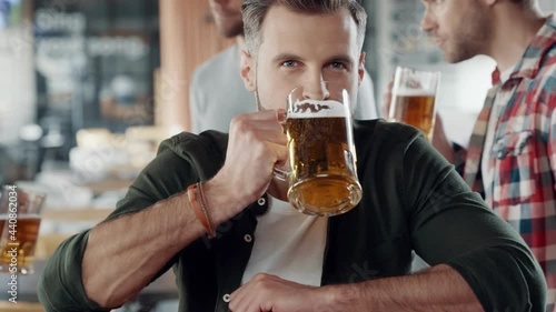 Wallpaper Mural Handsome young man drinking beer while spending time with friends in the pub Torontodigital.ca