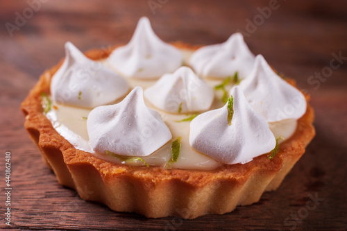 closeup of a small lemon pie on a wooden table with selective focus on the front of the pie