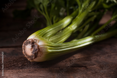 celery on a rustic wooden table with small rays of light coming in through the window, selective focus and blurred background