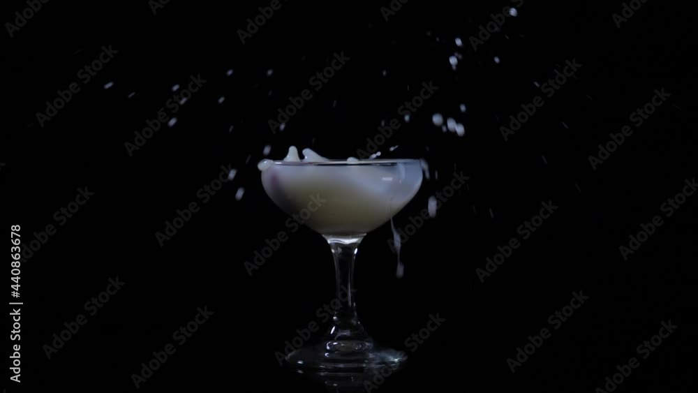 Milk is poured into a glass on a black background, slow motion Milk is poured into a glass on a black background, slow motion