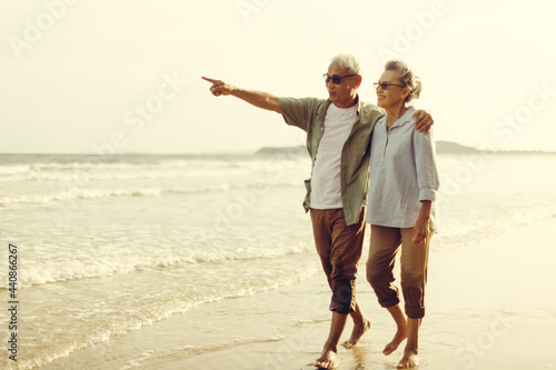 Romantic Senior couple strolling happily along the beach in the evening sun. Plan life insurance and retirement concept.