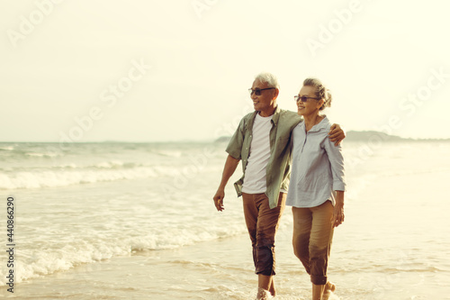 Romantic Senior couple strolling happily along the beach in the evening sun. Plan life insurance and retirement concept.