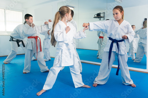 Cheerful kids sparring in pairs to practice new moves in karate class