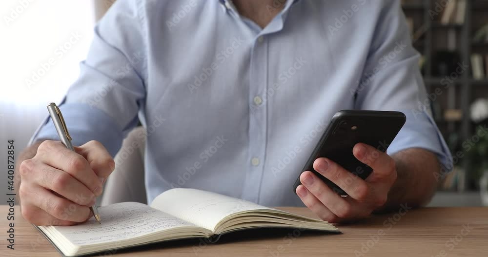 Close up cropped view man sit at desk holding smartphone write agenda on  diary, plan daily business appointment use personal calendar, makes to-do  list. Internet information resources usage concept