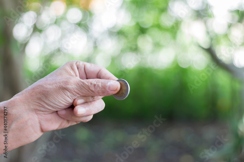 Man's hand holding a coin on a blurry background ©  Mushroom House