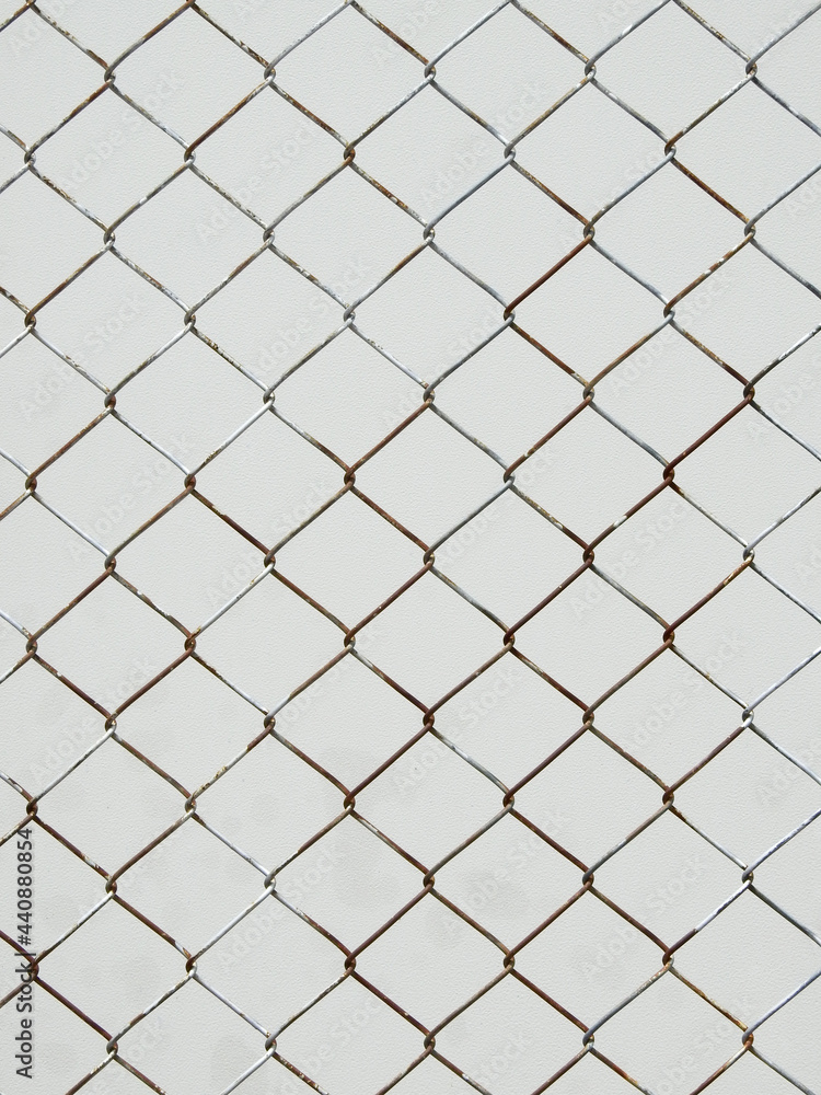old wire mesh of fence with white metal wall background old wire mesh of fence with white metal wall background
