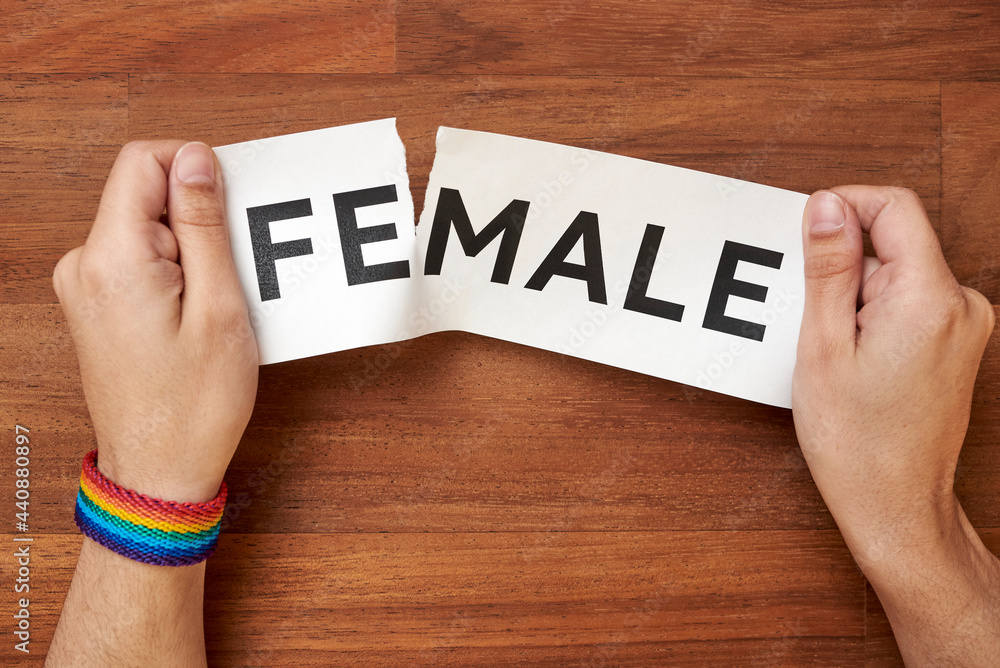Hands ripping the word female, leaving male, wearing a rainbow lgbt bracelet Hands ripping the word female, leaving male, wearing a rainbow lgbt bracelet