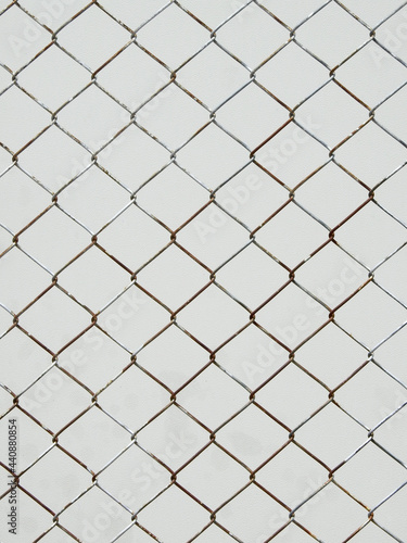 old wire mesh of fence with white metal wall background