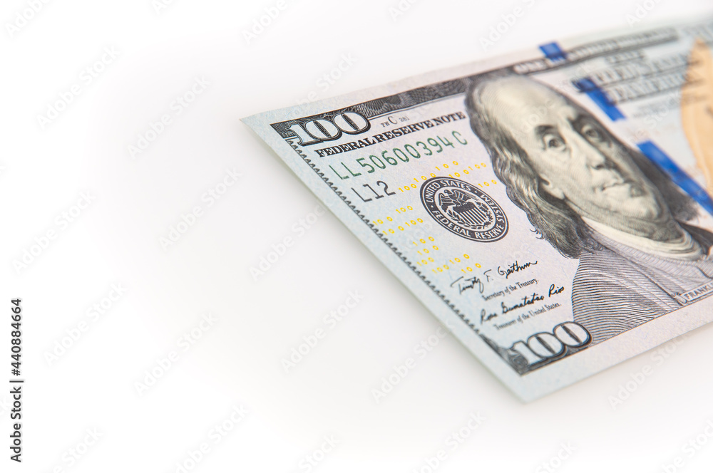 A hundred-dollar bill on a white background. The one hundred North American dollars bill is not fully positioned diagonally. Selective focus on a portion of the 100 bill. Color style. A hundred-dollar bill on a white background. The one hundred North American dollars bill is not fully positioned diagonally. Selective focus on a portion of the 100 bill. Color style.
