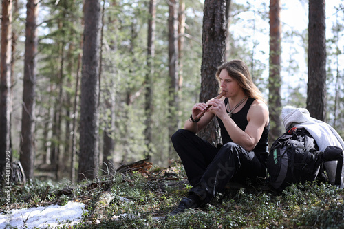 A musician with a tool in nature. A man is playing a flute in a pine forest. The music of the druids in the spring forest. © alexkich